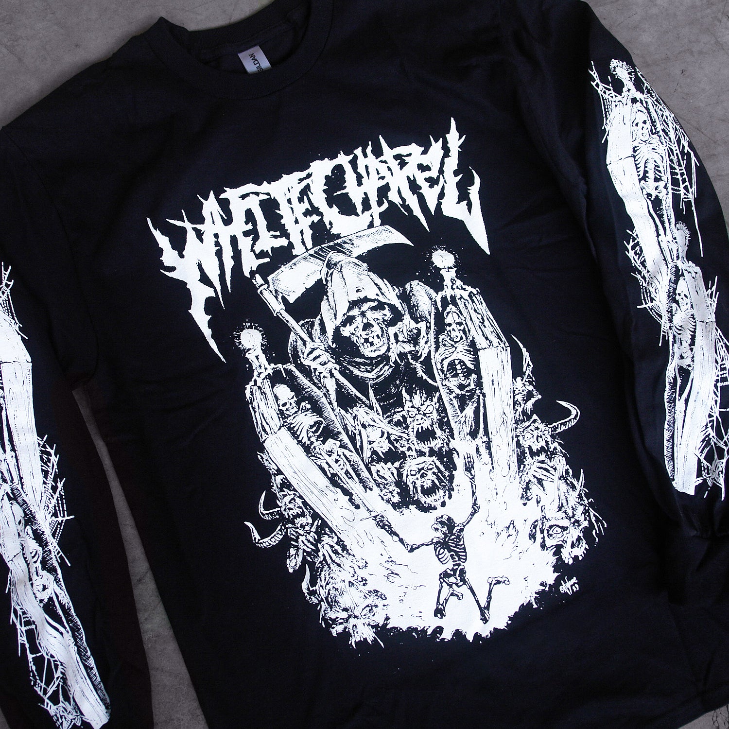 close up image of a black long sleeve tee shirt laid on a concrete floor. front has full body print in white of a grim reaper looking over a skeleton. at the top says whitechapel. each sleeve has prints of skeletons in coffins