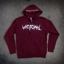 Load image into Gallery viewer, image of a maroon zip up hoodie laid flat on a concrete floor.  front of the hoodie is on the left and has a white print across the chest that says whitechapel. the hood is in the middle and shows a white print across the brim that says possession.
