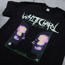 Load image into Gallery viewer, up close Image of a black tshirt against a grey concrete background. Across the chest of the shirt in white heavy metal font reads &quot;whitechapel&quot;. Below this there is a green outline of a square. The inside of the square features a graphic of the side profiles of two faces. They have pink, yellow, and blue splotches on their heads and noses. There is a small white sawblade with three stars in the center of it on the right side of the shirt. 
