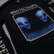 Load image into Gallery viewer, close up Image of a black longsleeve against a grey concrete background. The crewneck features the heads of two skulls, looking at one another. This is in blue. They are made up of blue and black static- and the static is beneath them too. This is outlined in a white square. Above the square in white text reads &quot;whitechapel&quot;. The left sleeve says &quot;Kin&quot; on it 5 times in white text. the right says &quot;whitechapel&quot;, just once, in white text.
