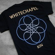 Load image into Gallery viewer, close up, angled image of the back of a black tee shirt on a concrete background. The back reads &quot;whitechapel&quot; across the shoulders in tan text. Below this is an abstract thin lined pattern in white and blue. It looks like a circle with lines and stars in the center. Below this in tan text reads &quot;kin&quot;.
