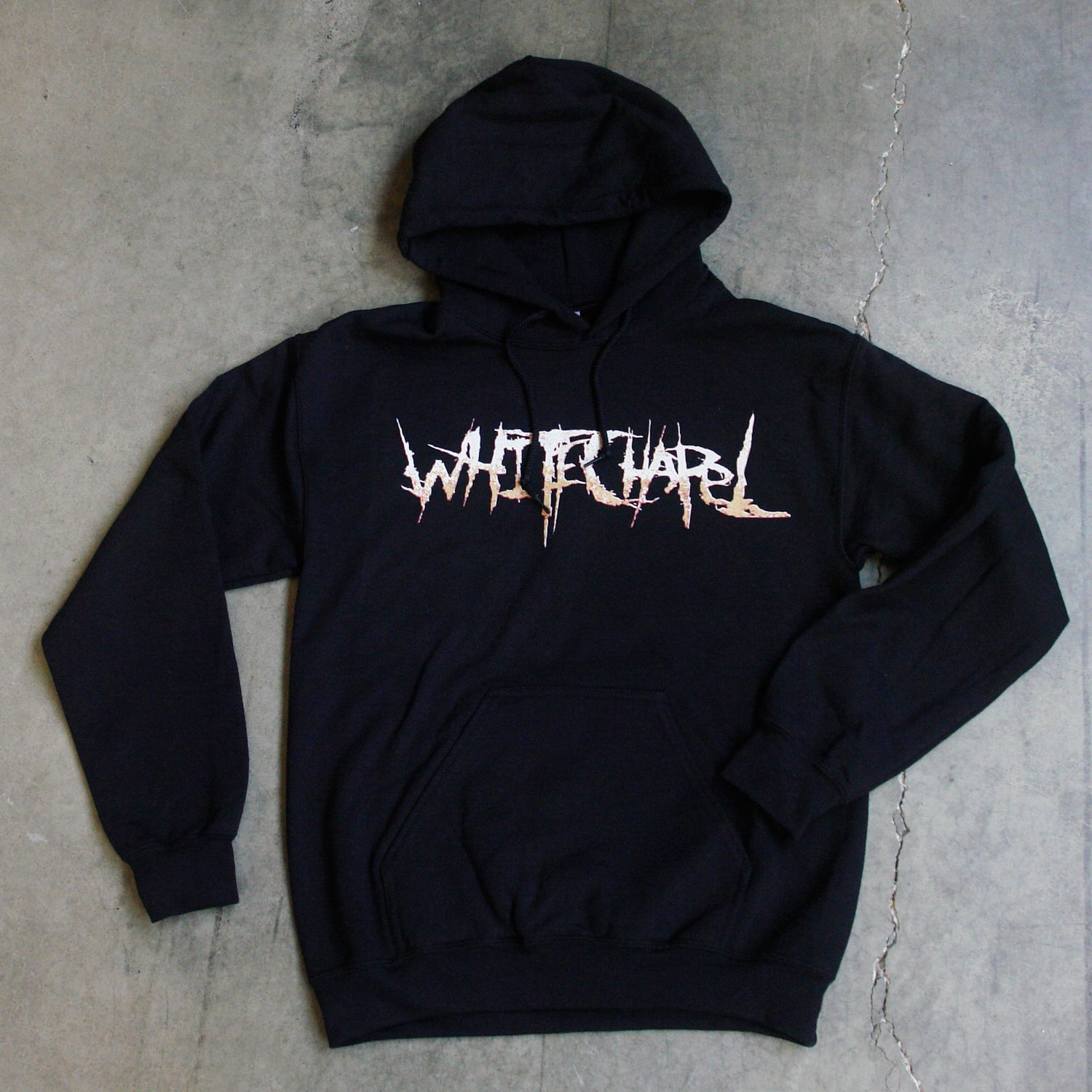 Image of the front of a black hooded sweatshirt against a grey concrete background. Across the chest in white to light orange gradient in heavy metal font reads whitechapel.