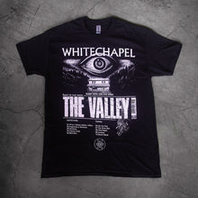 Load image into Gallery viewer, image of a black tee shirt laid flat on a concrete floor. tee has full body print in white of a giant eye above a house. at the top says whitechapel and below says the valley
