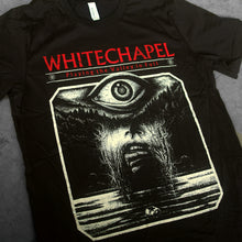 Load image into Gallery viewer, close up, angled image of a black tee shirt laid flat on a concrete floor. tee has full print of an eye coming of out water. at the top in red says whitechapel playing the valley in full
