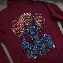 Load image into Gallery viewer, image of the back of a maroon hoodie laid flat on a concrete floor. the hoodie has a full back print of a goat like god figure
