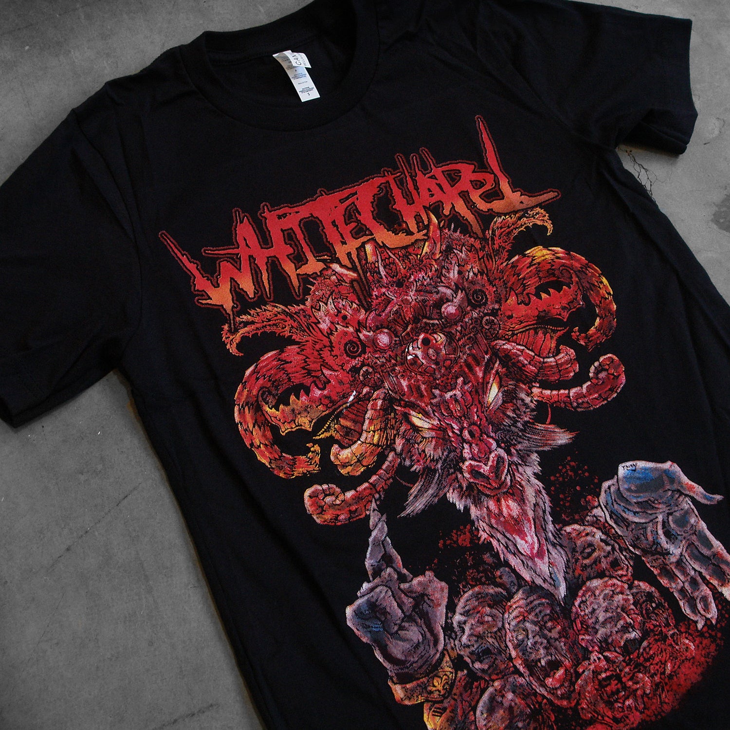 image of a black tee shirt. tee has full color body print of a demon medusa like head. at the top says whitechapel