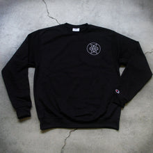 Load image into Gallery viewer, Image of the front of a black crewneck against a grey concrete background. The left chest has what is called a double pentagram, it is a white circle with two stars mirroring and slightly overlapping each other on the inside of the circle. The left sleeve has the champion &quot;C&quot; red white and blue logo on it. 
