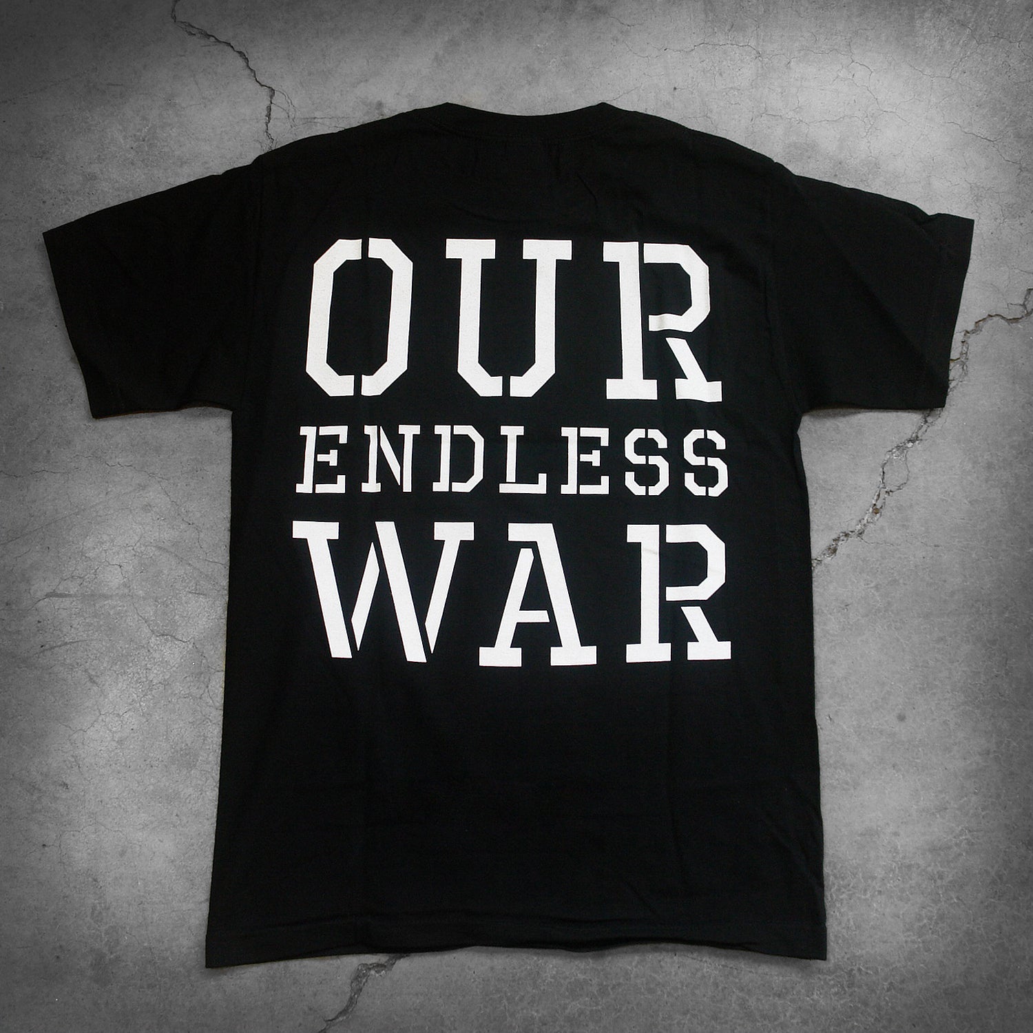 image of the back of a black tee shirt on a white background. the back of the shirt in large white text reads "our endless war".