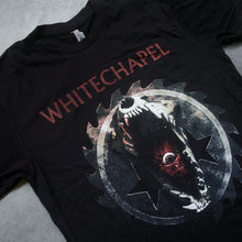 Load image into Gallery viewer, up close Image of the front of a black tshirt against a grey concrete background. Across the chest in red text reads &quot;whitechapel&quot;. The lettering is slightly distressed. Below this is a graphic of a sawblade with three black stars int the center. On top of this is a wide open jaw of an animal, inside its mouth is an up close eye. 
