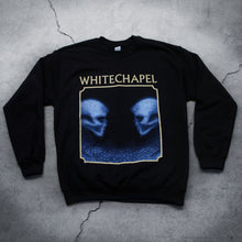 Load image into Gallery viewer, Image of a black crewneck against a grey concrete background. The crewneck features the heads of two skulls, looking at one another. This is in blue. They are made up of blue and black static- and the static is beneath them too. This is outlined in an off white square. Above the square in an off white text reads &quot;whitechapel&quot;.
