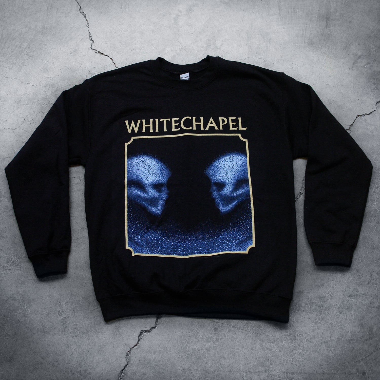 Image of a black crewneck against a grey concrete background. The crewneck features the heads of two skulls, looking at one another. This is in blue. They are made up of blue and black static- and the static is beneath them too. This is outlined in an off white square. Above the square in an off white text reads 