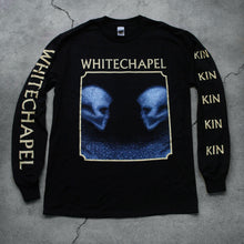 Load image into Gallery viewer, Image of a black longsleeve against a grey concrete background. The crewneck features the heads of two skulls, looking at one another. This is in blue. They are made up of blue and black static- and the static is beneath them too. This is outlined in a white square. Above the square in white text reads &quot;whitechapel&quot;. The left sleeve says &quot;Kin&quot; on it 5 times in white text. the right says &quot;whitechapel&quot;, just once, in white text.
