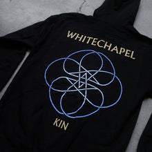 Load image into Gallery viewer, close up Image of the back of a black zip up sweatshirt against a grey concrete background. Across the shoulder area in white text reads &quot;whitechapel&quot;. Below this is a circular lined abstract design with two stars in the center, designed to look like a double pentagram. This is white and blue. Below this design in white text reads &quot;Kin&quot;.
