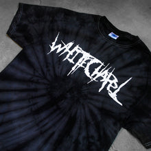 Load image into Gallery viewer, close up, angled image of a black spider tie dye tee shirt on a cracked concrete background. tee has front center chest print across in white that says Whitechapel
