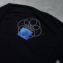 Load image into Gallery viewer, up close  Image of the back of a black long sleeve against a grey concrete background. The sleeves feature a white circle abstract design with lines and two stars in the center making a double pentagram. The back center of the shirt near the shoulders features a white circle outline with abstract lines in the center, and two stars making a double pentagram. a blue square is underneath this. In small blue text reads &quot;orphan&quot;. This is placed across the circle design.
