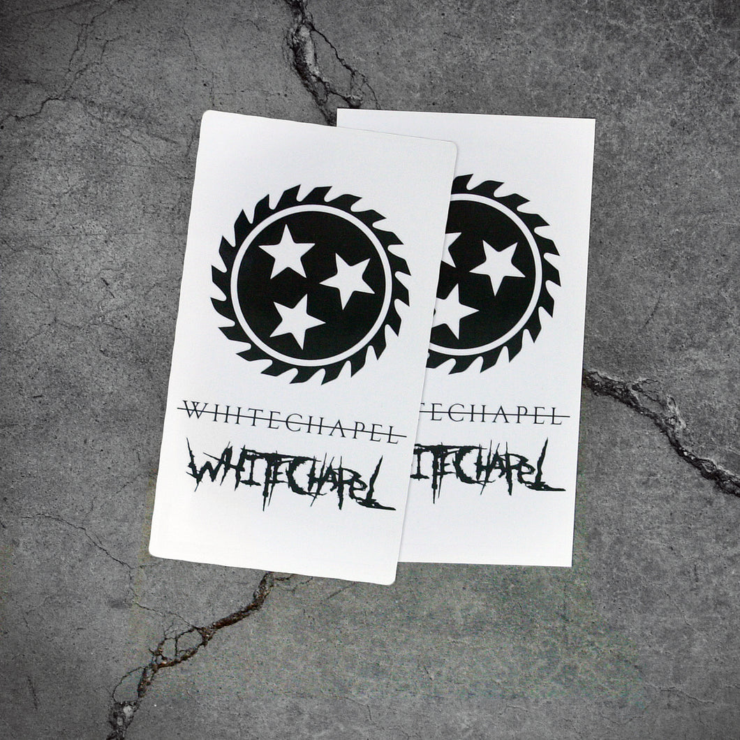 Image of two white pieces of paper with temporary tattoos on them against a grey concrete background. There is a black sawblade with three white stars in the center of it. There is the word whitechapel in black text with a thin black line through it, and the word whitechapel in black heavy metal style font. Both sheets are identical.