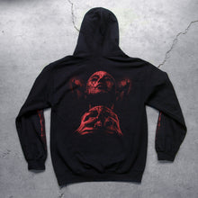 Load image into Gallery viewer,  Image of the back of a black hoodie against a concrete grey background.  There is a red graphic of a person&#39;s face with their eyes closed, head up. They have blood on them and are clutching a skull.  The sleeves feature red graphics that are abstract and drip blood.
