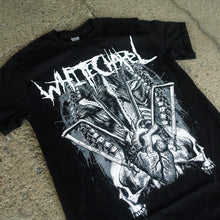 Load image into Gallery viewer, Image of the front of a black tshirt against a grey concrete background. The front of the shirt says &quot;whitechapel&quot; across the chest in white heavy metal style font. Below that is a white, grey, and black graphic of spines, a heart, bones, and two skeleton skulls, one facing towards the left, and the other mirrored, facing towards the right. 
