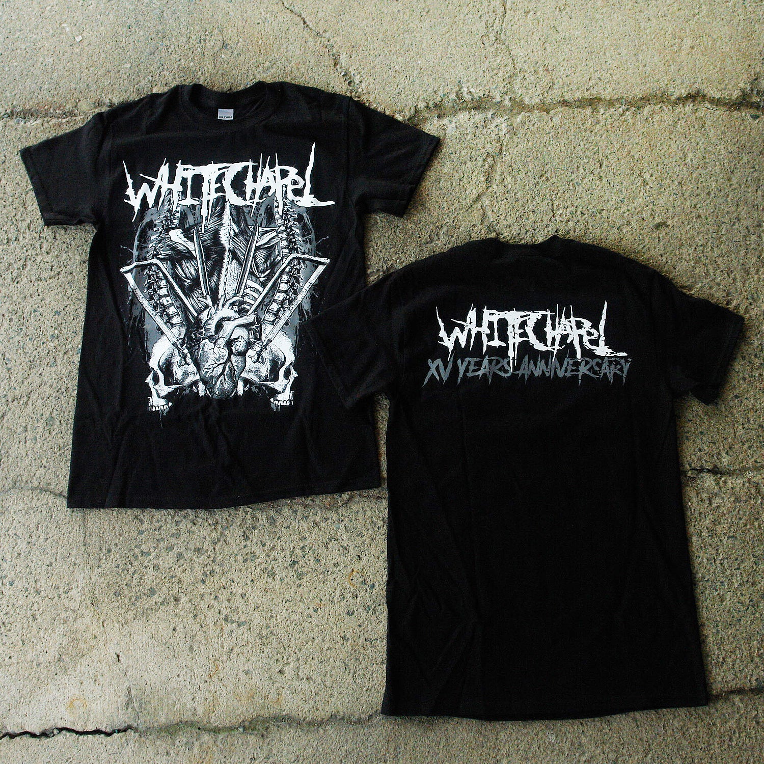 Image of the front and back of a black tshirt against a grey concrete background. The front of the shirt says 