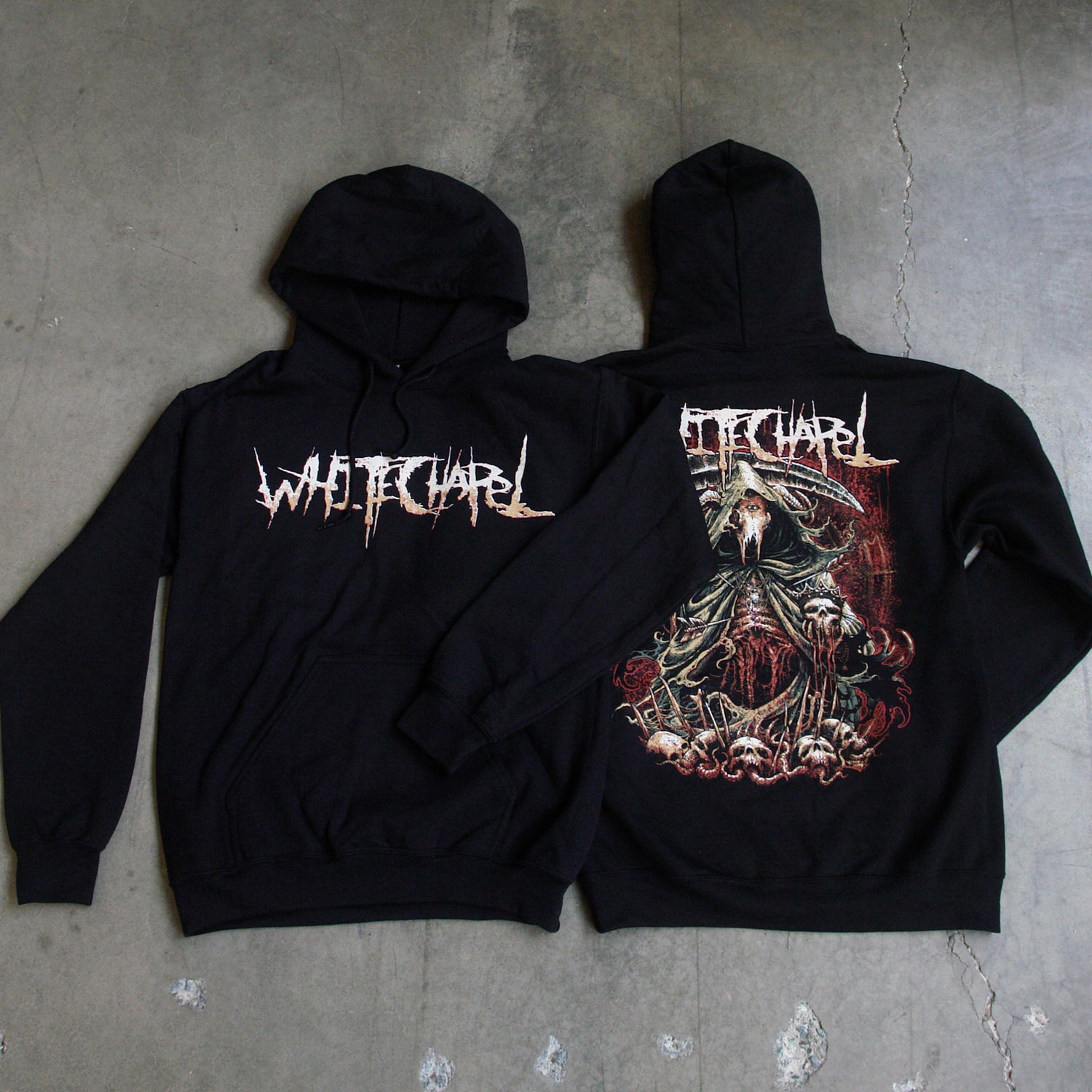 Image of the front and back of a black hooded sweatshirt against a grey concrete background. Across the chest in white to light orange gradient in heavy metal font reads whitechapel. the back features a red, white, black, and bluish gray graphic of a an animal skull with a third eye holding a scythe and wearing a cloak. Its ribs are showing. There are skull heads all around the monster. There is a red background behind the graphic.