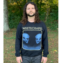 Load image into Gallery viewer, Image of a man with medium length curly brunette hair wearing a black crewneck and dark blue jeans standing in a forest. The crewneck features the heads of two skulls, looking at one another. This is in blue. They are made up of blue and black static- and the static is beneath them too. This is outlined in an off white square. Above the square in an off white text reads &quot;whitechapel&quot;.

